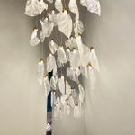 Close-up of sculpted optical acrylic leaf blade showing realistic leaf vein textures and flower-bud cap light source on a luxury chandelier