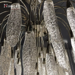 Close-up of textured optical acrylic feather leaf pods with zinc alloy hardware on a steel frame chandelier