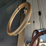 Close-up of terracotta bronze aluminum hoop ring showing smooth matte texture and suspension cable attachment