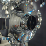 Close-up of thick optical crystal lens disc with halo LED lighting on a mirror chrome ring chandelier
