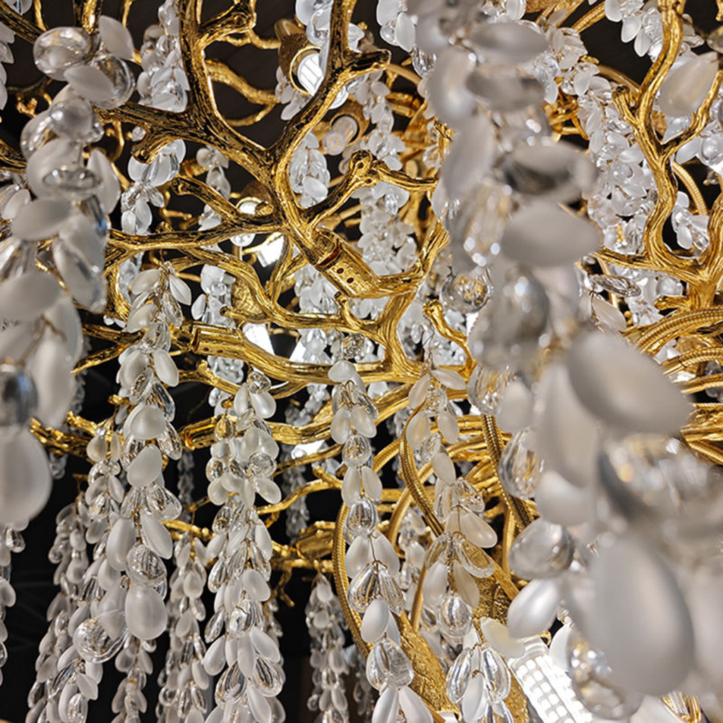 Close-up of golden textured cast aluminum branches with clear and frosted wisteria crystal drops on a luxury chandelier