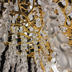 Close-up of golden textured cast aluminum branches with clear and frosted wisteria crystal drops on a luxury chandelier