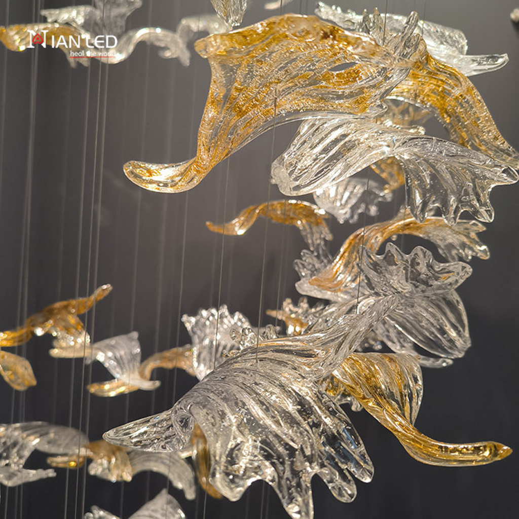 Close-up of wave-textured clear and gold foil crystal bird blades on a luxury pendant chandelier