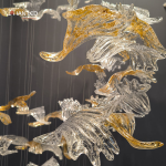 Close-up of wave-textured clear and gold foil crystal bird blades on a luxury pendant chandelier