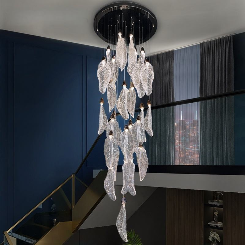 Tall stainless steel and textured acrylic leaf cascade chandelier suspended in a high-ceiling stairwell void