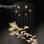 Close-up of wave-textured clear and gold foil crystal bird blades on a luxury pendant chandelier