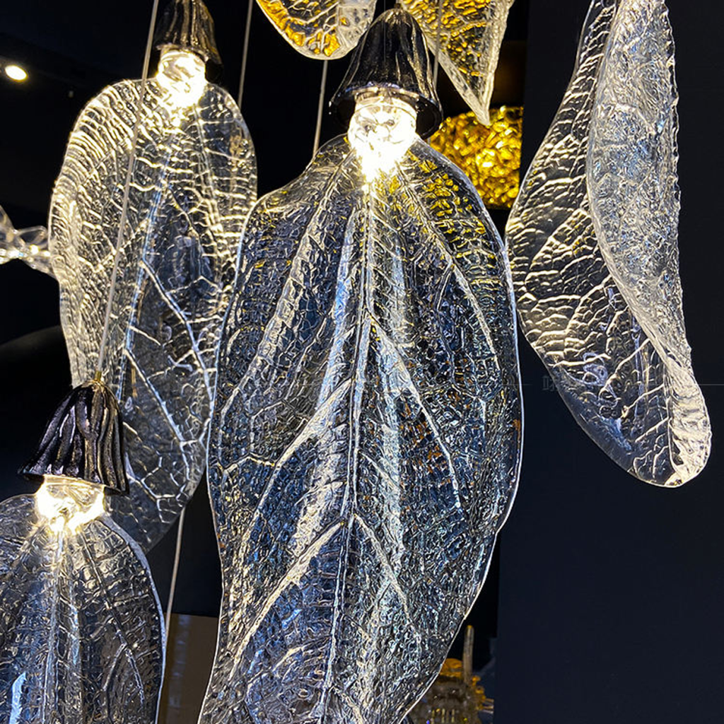 Close-up of sculpted optical acrylic leaf blade showing realistic leaf vein textures and flower-bud cap light source on a luxury chandelier