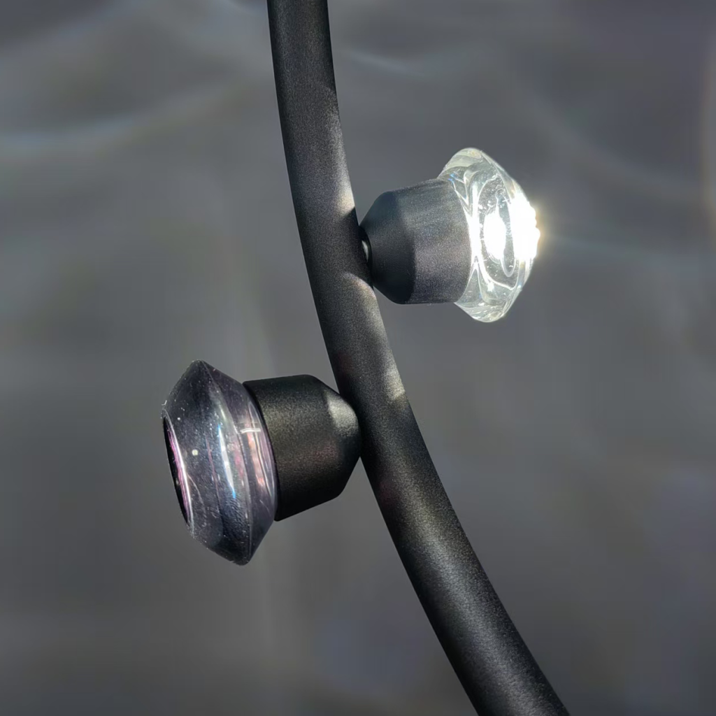 Macro view of optical crystal lens showing integrated LED chip inside matte black aluminum housing