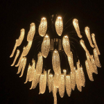 Illuminated optical acrylic cascade chandelier casting warm ambient light for high ceiling living room and foyer