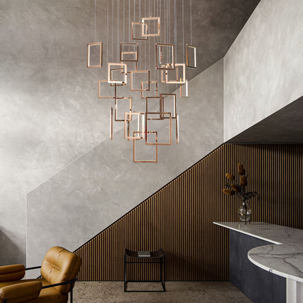 Modern rose gold stainless steel square frame cascade chandelier with mirror canopy suspended in a high ceiling foyer