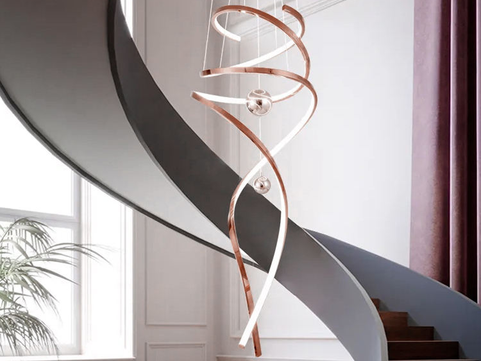 Modern rose gold stainless steel helical helix LED wave pendant light with floating orb spheres suspended in a high ceiling foyer
