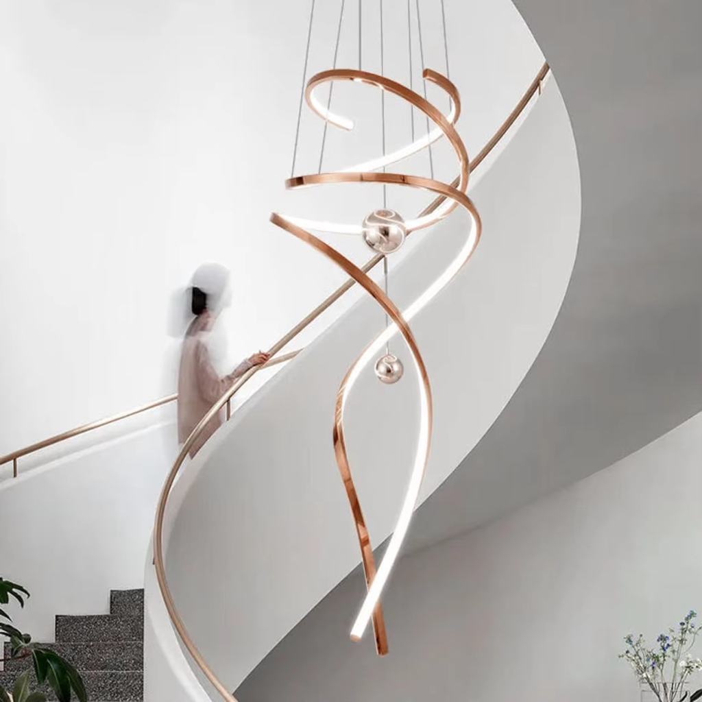 Modern rose gold stainless steel helical helix LED wave pendant light with floating orb spheres suspended in a high ceiling foyer