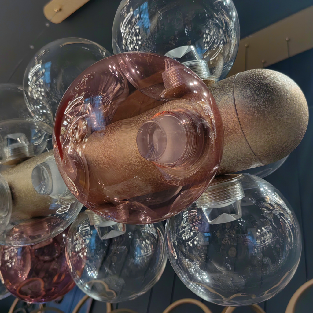 End view of blush pink and clear glass globes attached to crackle gold textured aluminum beamEnd view of blush pink and clear glass globes attached to crackle gold textured aluminum beam