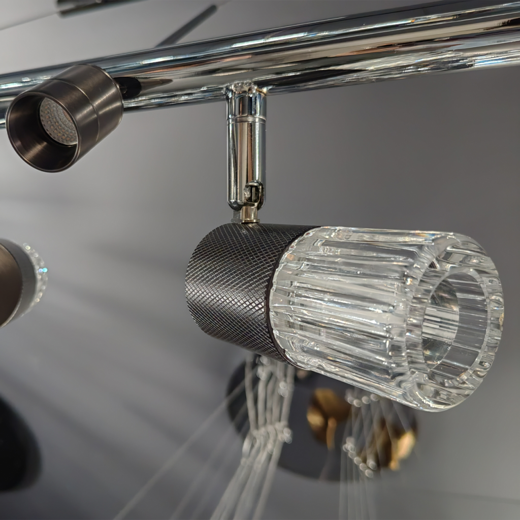 Close up of diamond knurled black metal spotlight socket with fluted glass shade attached to chrome swivel joint