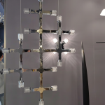 The Lattice modular chrome grid chandelier with multi directional crystal light heads hanging against wall