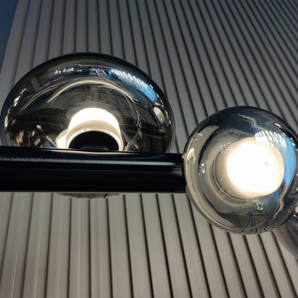 Close up of illuminated frosted LED bulb inside smoky translucent glass sphere on matte black bar