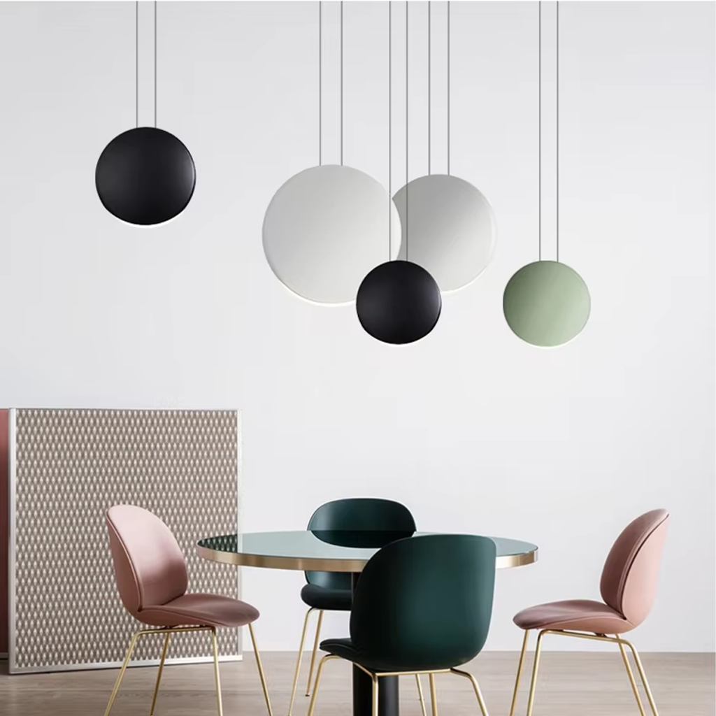 Close-up of matte grey, black, and white polyresin disc light shades showing crescent LED illumination and metal suspension cords