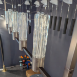 Close up of vertical fluted glass shade mounted on diamond knurled metal base on black linear frame