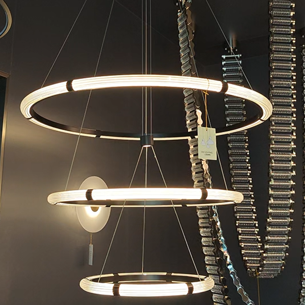 The Aura cascading 3 ring LED pendant fixture glowing warm white against dark background