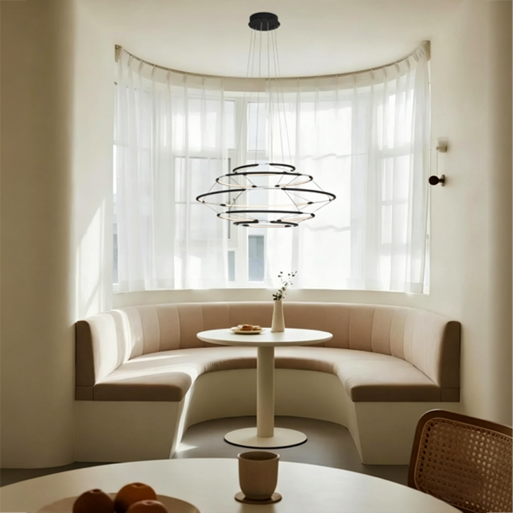 The Orbital Mesh multi tier LED ring chandelier hanging over a round dining table in a modern sunroom nook
