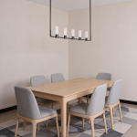 The Atelier matte black rectangular linear chandelier hanging over a wooden dining table in a luxury apartment