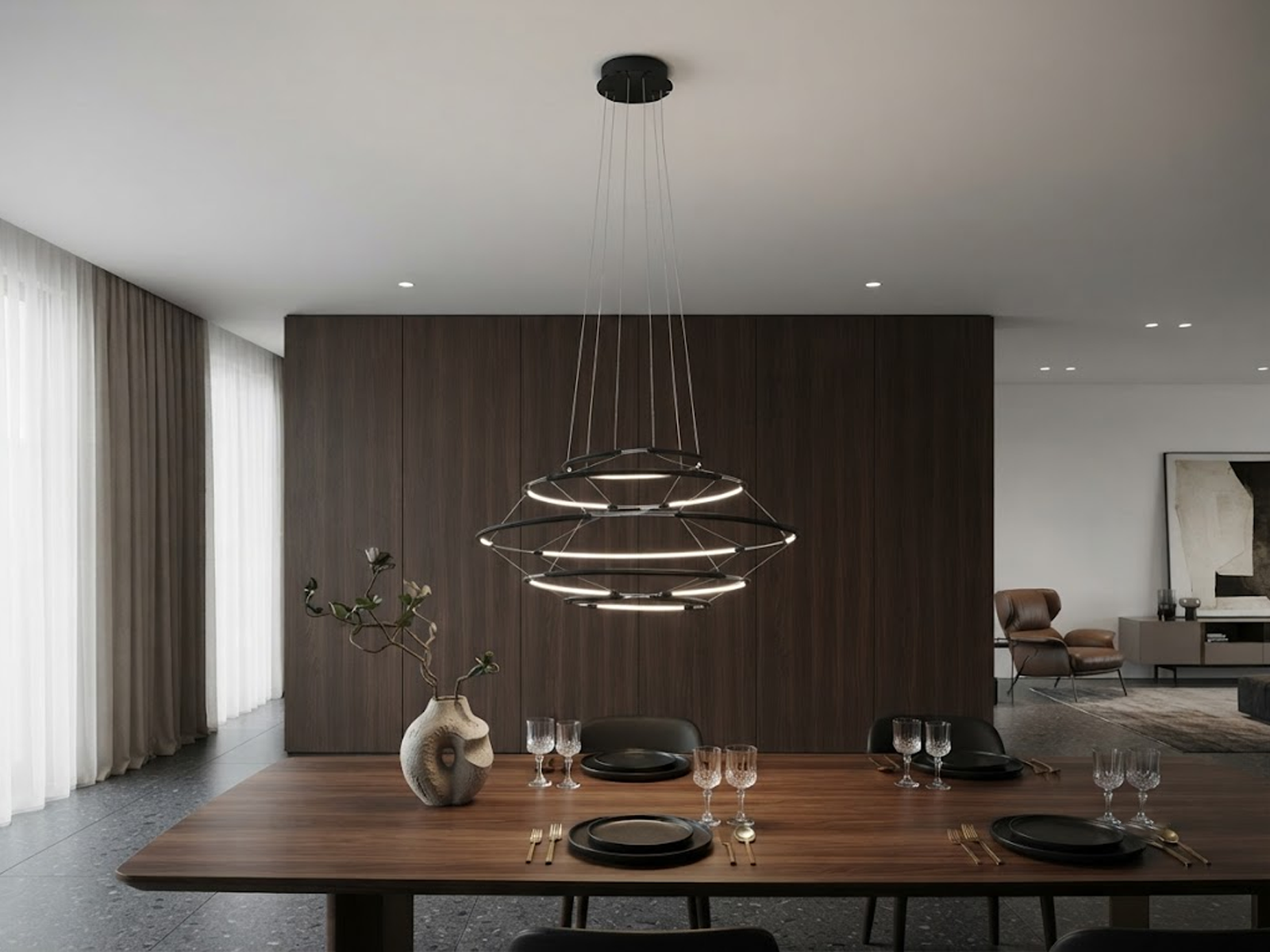 The Orbital Mesh multi tier LED ring chandelier hanging over a round dining table in a modern sunroom nook