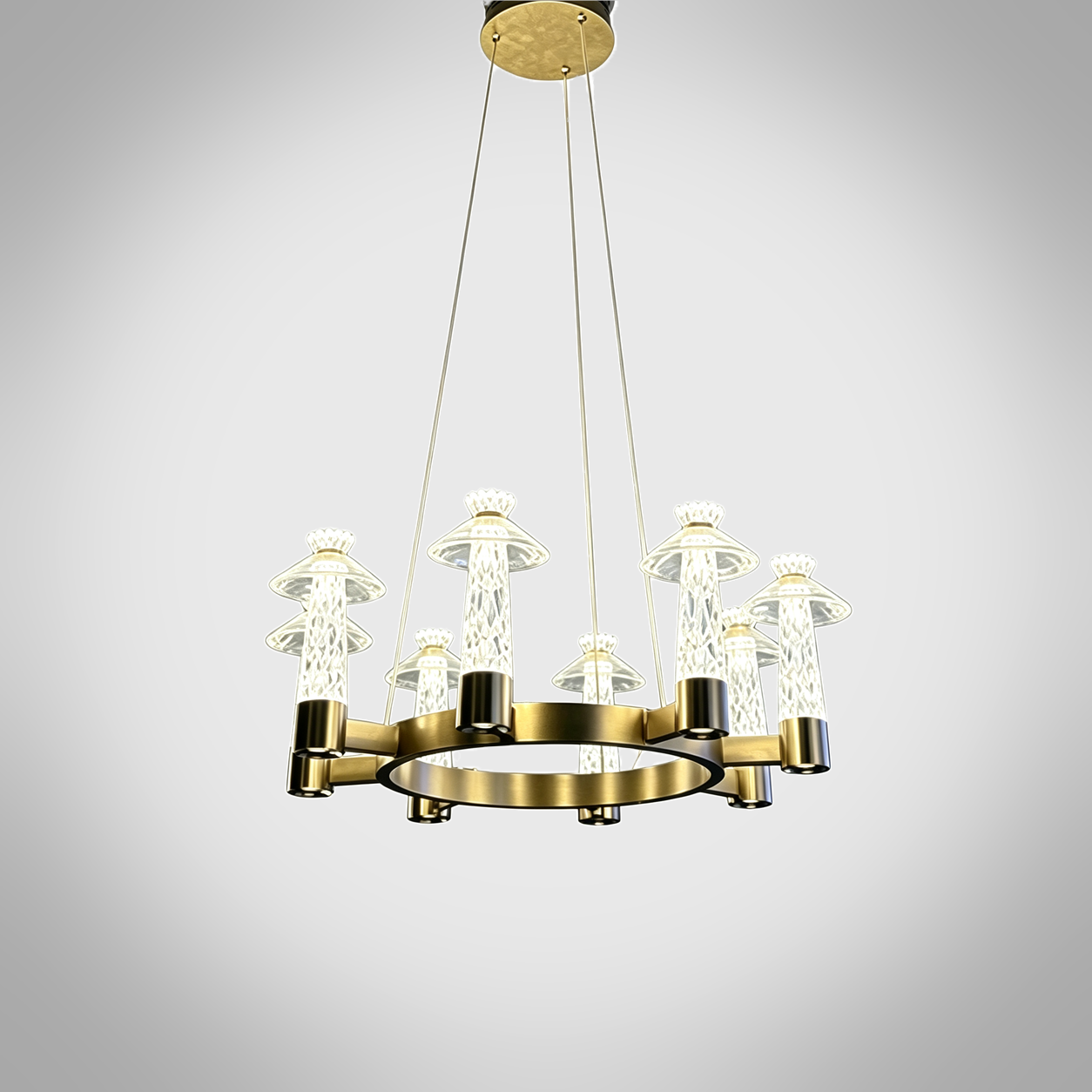 Carved crystal ring chandelier with brushed brass stainless steel frame suspended over a marble dining table in a luxury dining room