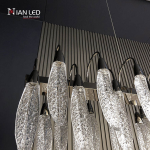 Side angle view of linear steel chandelier frame showing zinc alloy curved suspension hooks and frosted acrylic feather diffusers