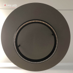 Upward view of glowing black aluminum LED ring showing micro-lenses and illuminated warm aluminum reflector disc