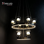 Two-tier stainless steel halo chandelier illuminated against dark background showing bottom ring light strips and glass orb cups