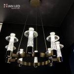 Glowing modern carved crystal ring chandelier with candle-like crystal shades shown against dark background