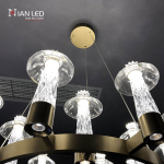 Close-up of glowing 3000K warm white carved crystal pillar and saucer shade on brushed brass stainless steel frame