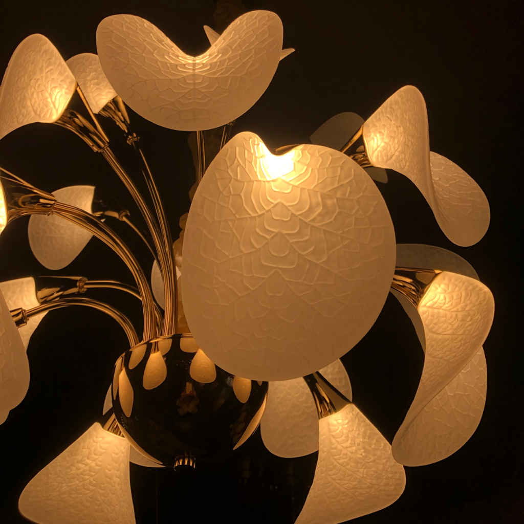 Close-up of frosted optical acrylic shade with leaf vein texture mounted on polished gold zinc alloy stem