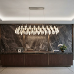 Large crystal-texture feather linear LED chandelier hanging above a luxury marble hotel reception desk in a contemporary lobby