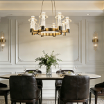 Carved crystal ring chandelier with brushed brass stainless steel frame suspended over a marble dining table in a luxury dining room